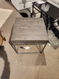 The Handstone Muskoka 24" End Table features a solid oak top and metal base, displayed on a carpeted showroom floor.