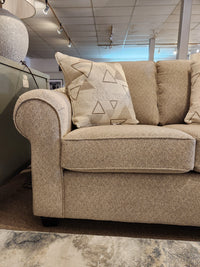 A Decor-rest 2179 Loveseat with rolled arms and patterned pillows is showcased on a light brown carpet.