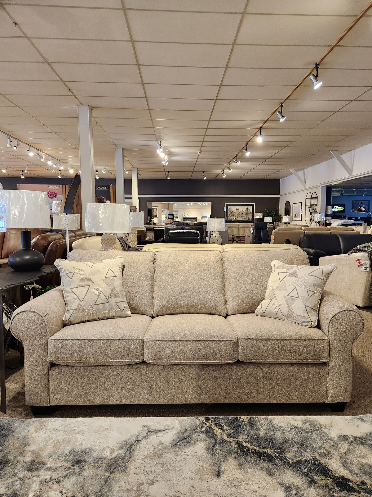2179 Queen sofabed by Decor-rest with patterned cushions, surrounded by furnishings in a stylish furniture store.