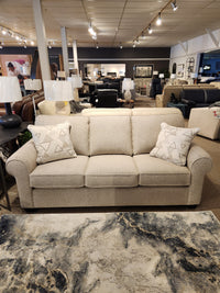 In a showroom, the Decor-rest 2179 Sofa in beige features stylish upholstery and patterned pillows among home decor items.
