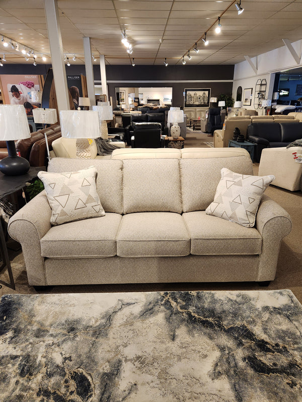 In a showroom, the Decor-rest 2179 Sofa in beige features stylish upholstery and patterned pillows among home decor items.