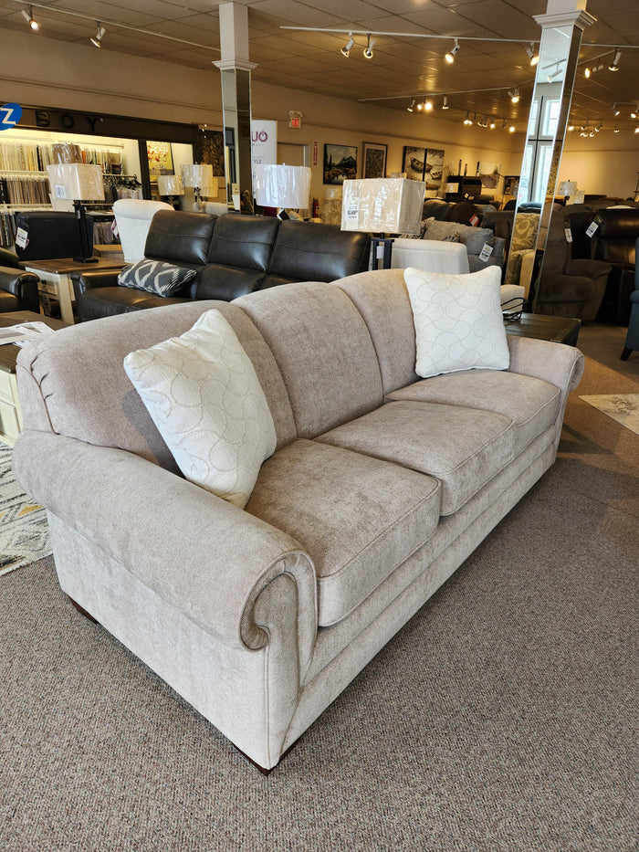 A La-Z-Boy 435 Mackenzie Queen Sofa Bed in gray with pillows is showcased in a furniture showroom.