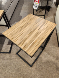 The AlaCarte Snack Table by Handstone features light wood grain on a black metal frame for versatile use near the sofa.