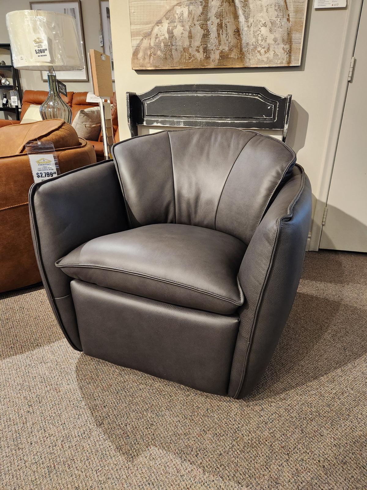 A modern dark gray 752 Swivel Chair by Leather Craft with cushioned seating, featured in a Toronto handmade furniture showroom.