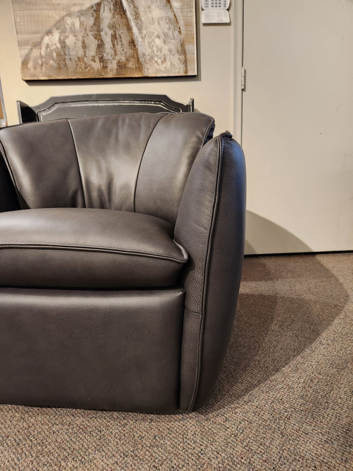 A black Leather Craft 752 Swivel Chair on a carpeted floor, beneath a painting and thermostat in a Toronto room.
