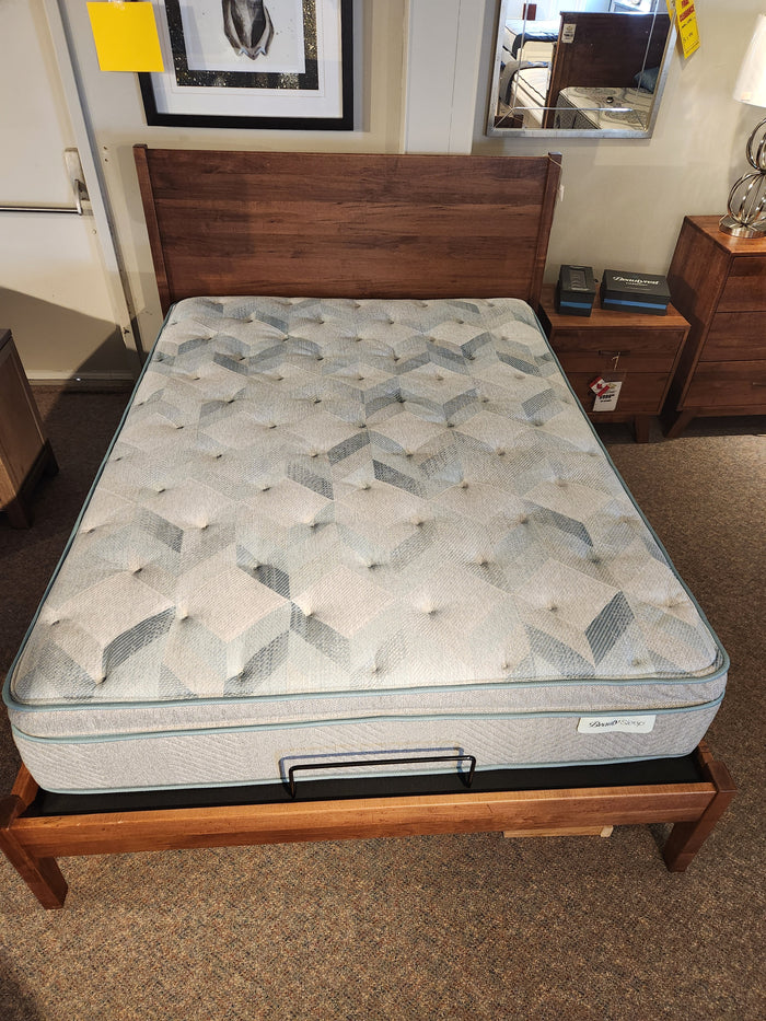 Wooden bed frame, Beauty-rest plush mattress, nightstand, and framed wall art displayed in the showroom.