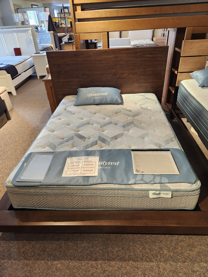 The Beauty-rest Erling Euro-Top Medium Mattress is showcased on a wooden bed frame with brochures and a sale sign.
