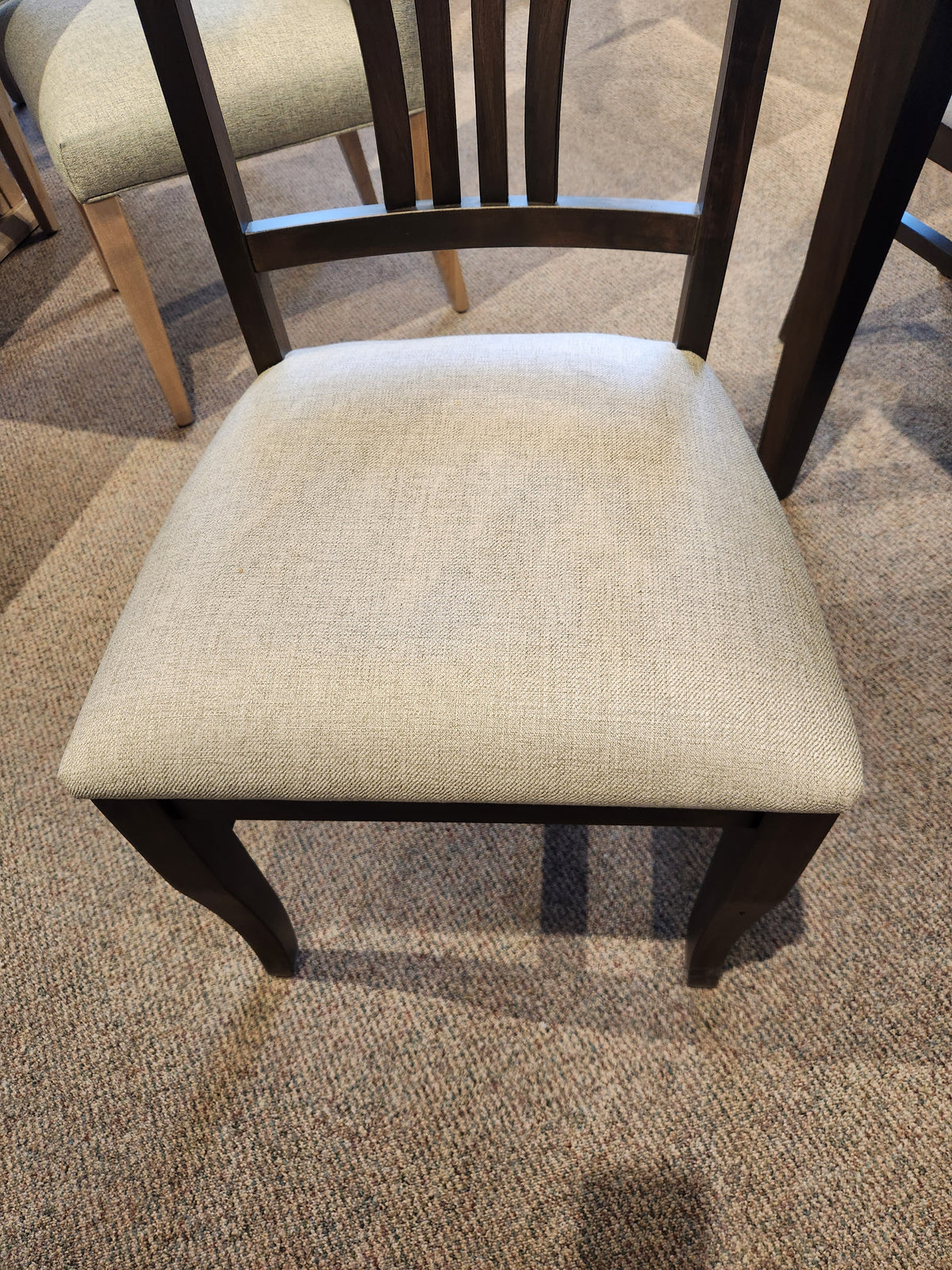 Handstone Parker chair from dining set with a light beige cushion on a carpeted floor.