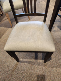 Handstone Parker chair from dining set with a light beige cushion on a carpeted floor.