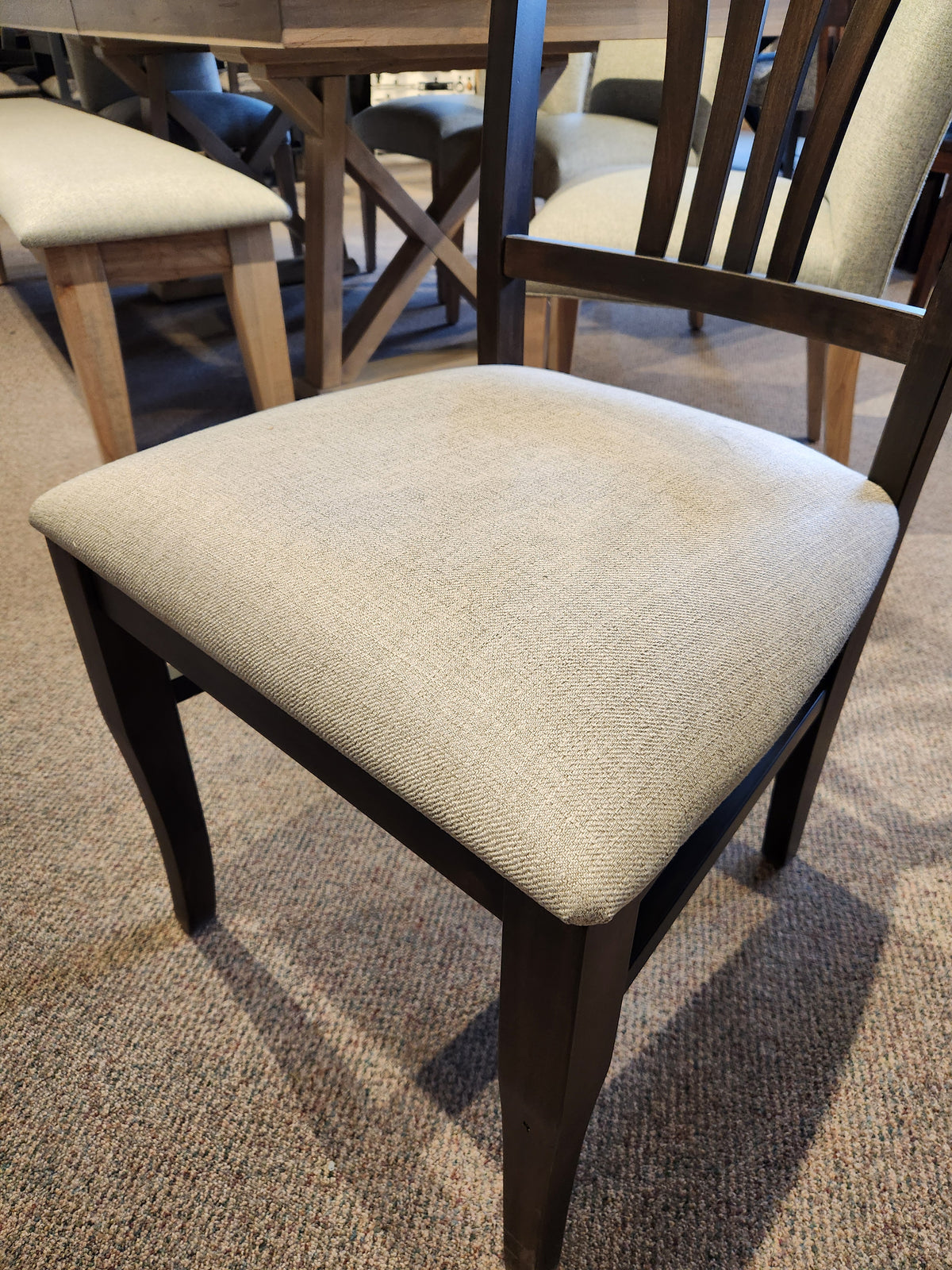 Handstone Parker 7pc Dining Package with a dining chair in light beige upholstery on carpet, near a matching table and bench.