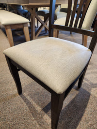 Handstone Parker 7pc Dining Package with a dining chair in light beige upholstery on carpet, near a matching table and bench.