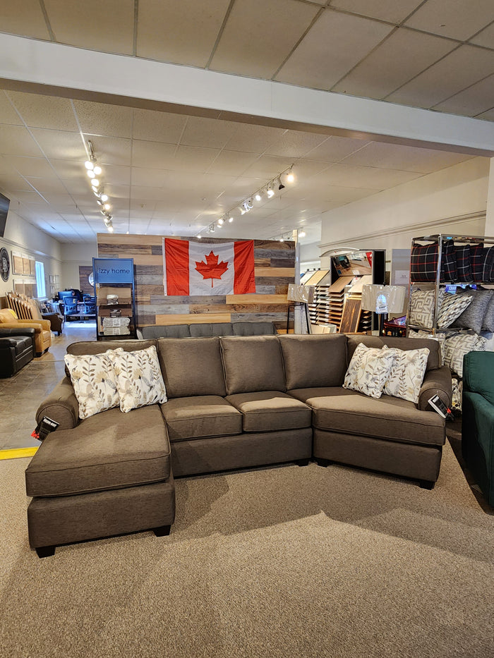 Decor-rest 2566/83 Sectional in a showroom with patterned pillows and a Canadian flag backdrop.