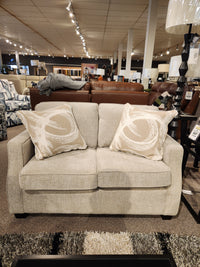 The 2570 Stationary Loveseat by Decor-rest, beige with two patterned cushions, is perfect for small showroom spaces.