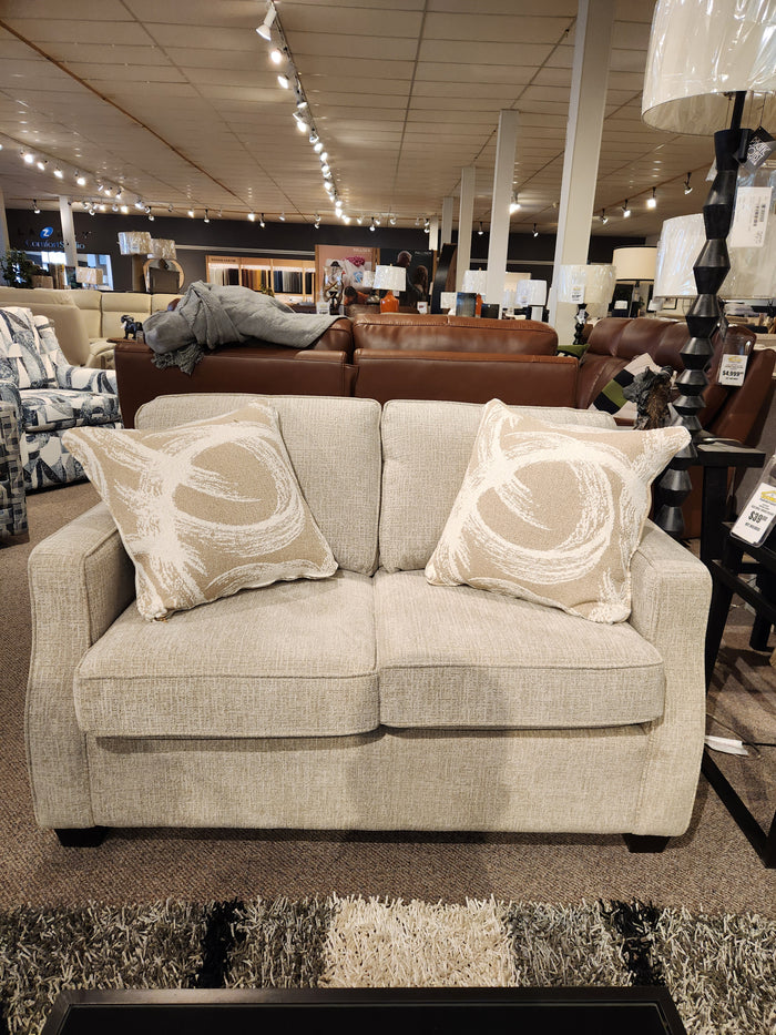 The 2570 Stationary Loveseat by Decor-rest, beige with two patterned cushions, is perfect for small showroom spaces.