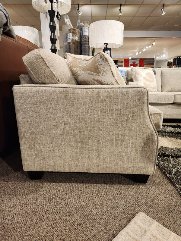 Side view of Decor-rest's 2570 Stationary Loveseat in beige fabric, featuring cushions, lamps, and small space decor.