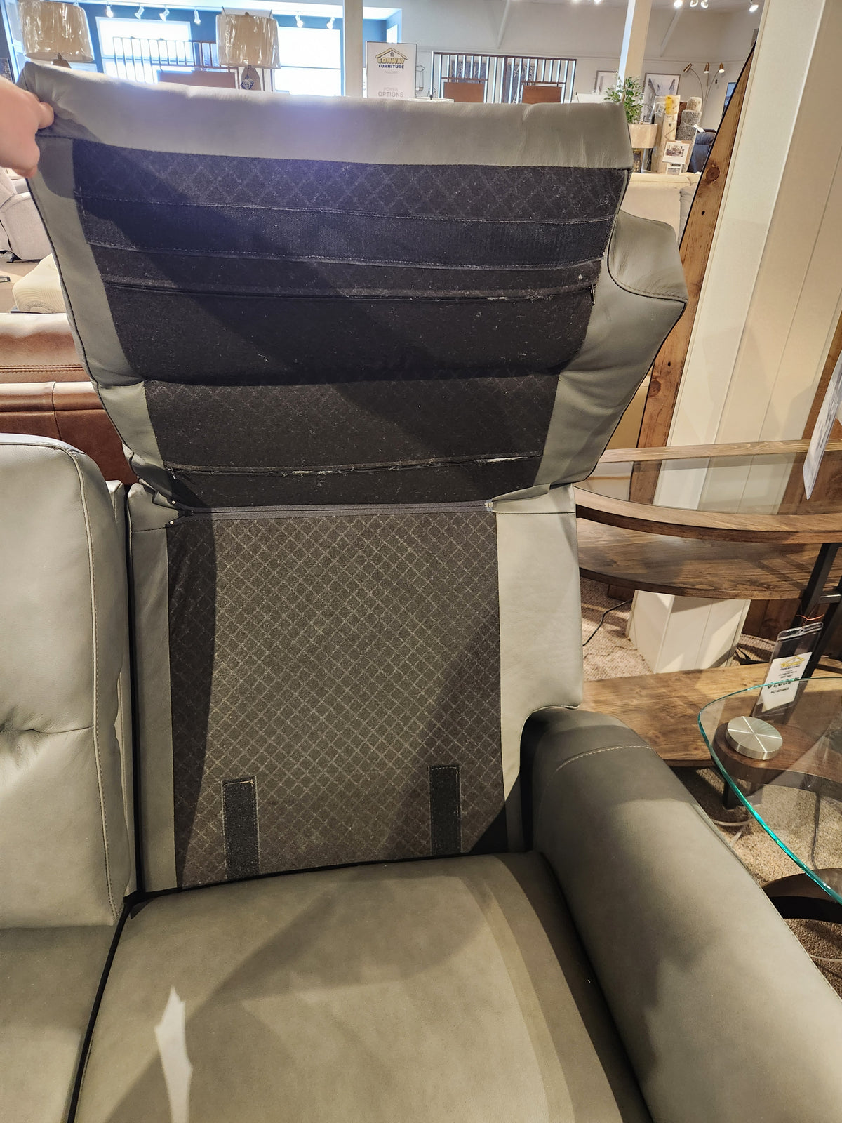 A person lifts the back panel of the Leather Craft Texas Power Reclining Sofa, revealing interior comfort support.