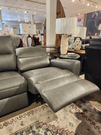 The Leather Craft Texas Power Reclining Sofa offers optimal comfort, shown in a showroom with lamp and decor.