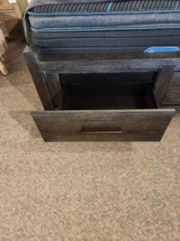 The Magnussen Plum Creek B5990 Queen Storage Bed features an open dark wood drawer with burnished bronze hardware.