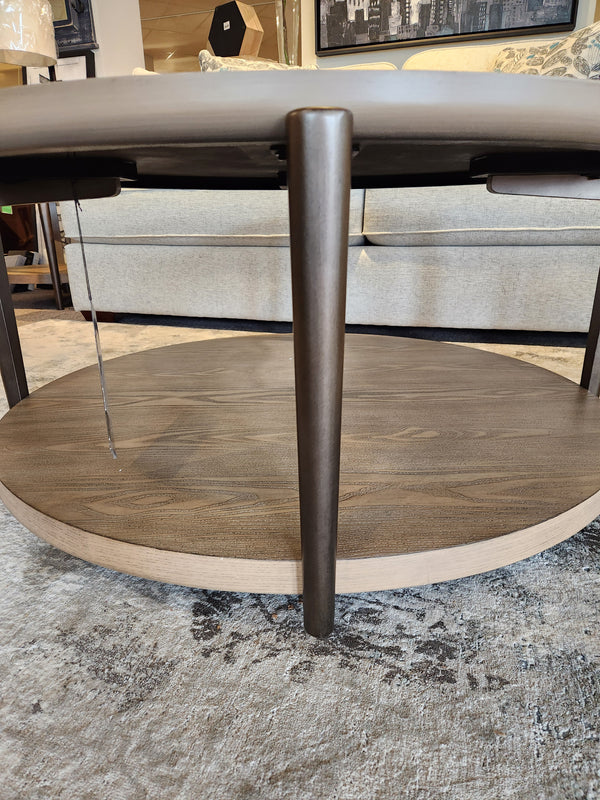 The Ashley Dyonton Round Cocktail Table adds an industrial and modern vibe in front of a beige sofa.