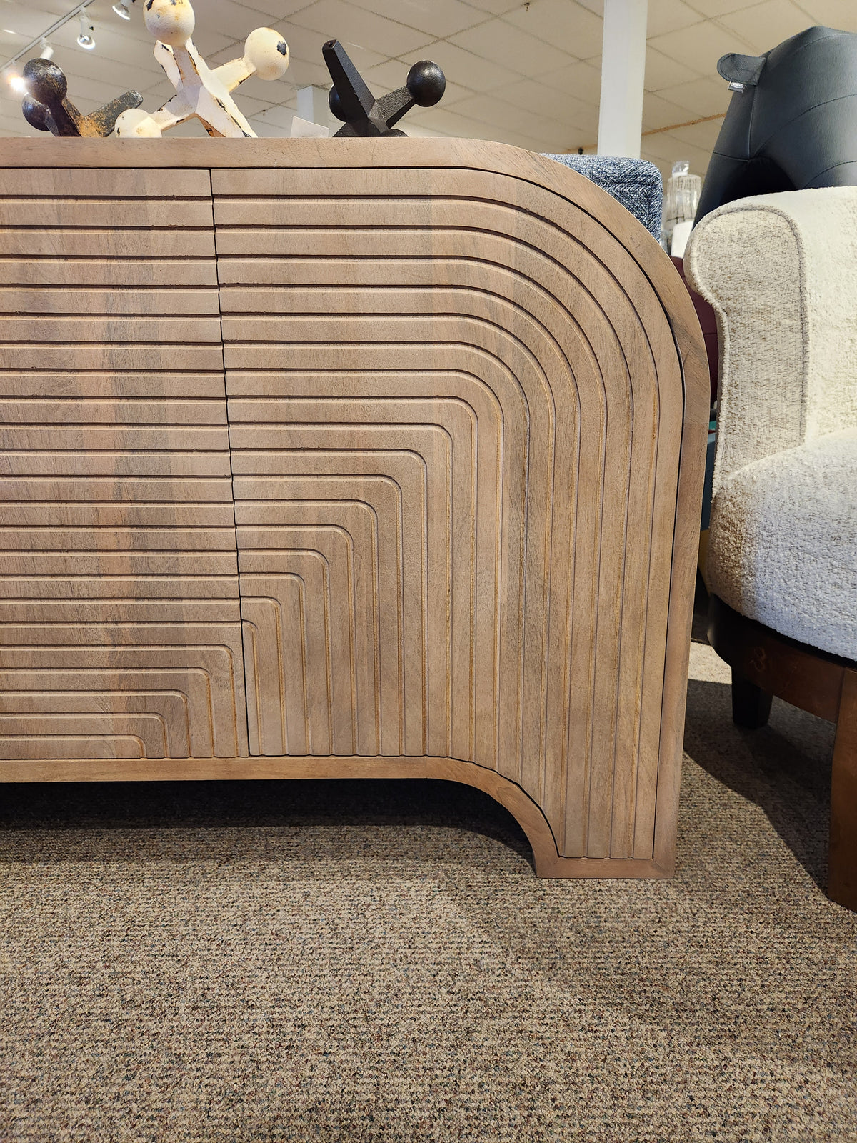 The Mercana 70838 Sorina Reverse Fluted Sideboard features curved geometric patterns and CNC doors on a carpeted floor.