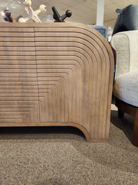 The Mercana 70838 Sorina Reverse Fluted Sideboard features curved geometric patterns and CNC doors on a carpeted floor.
