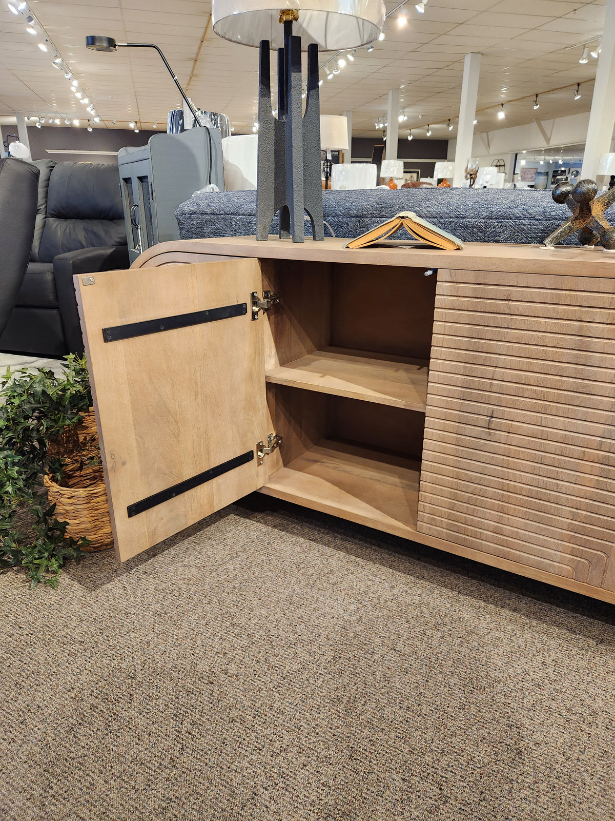 The Mercana 70838 Sorina Reverse Fluted Sideboard with one door open reveals two shelves in a showroom display.