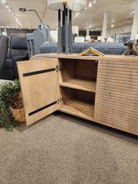 The Mercana 70838 Sorina Reverse Fluted Sideboard with one door open reveals two shelves in a showroom display.