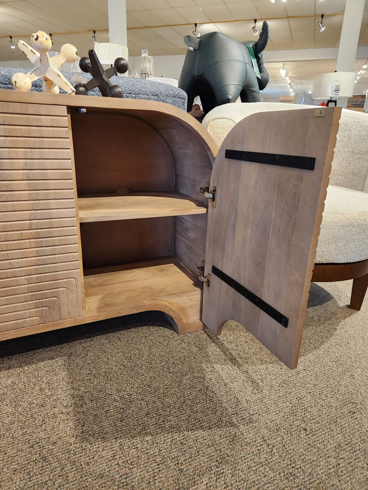 Mercana 70838 Sorina Reverse Fluted Sideboard with open door and shelves, shown on a carpeted floor.