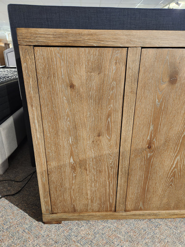 Close-up of the Nia Sideboard by Donald Choi, featuring two doors and a natural wood grain finish on a carpeted floor.