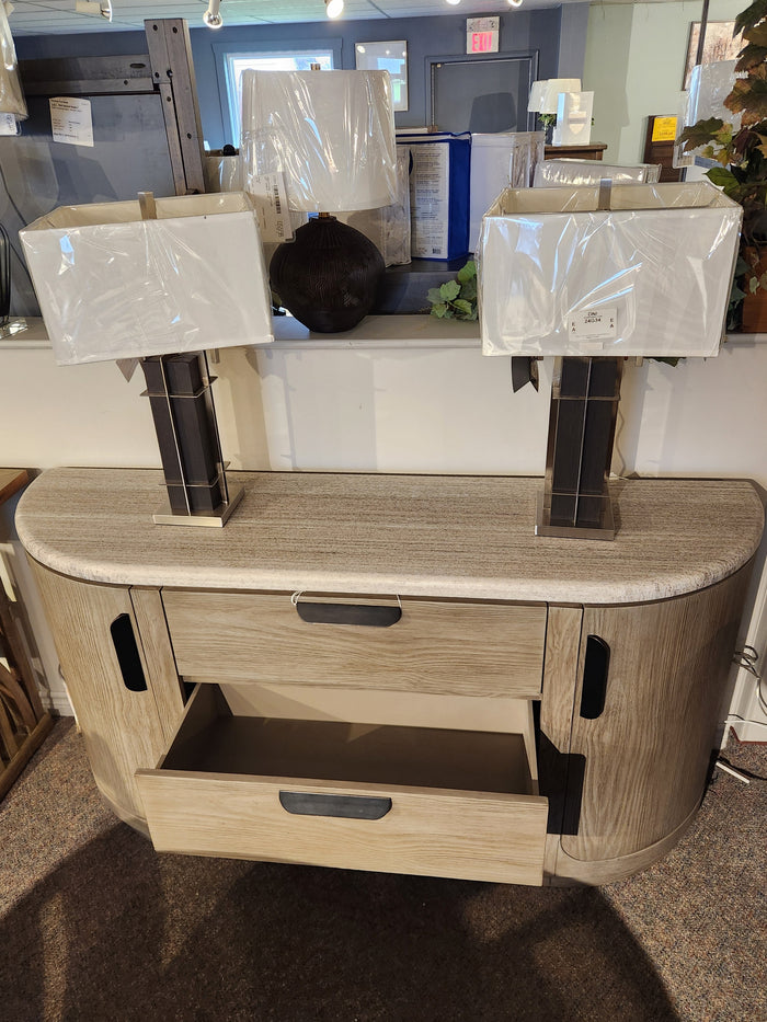 Magnussen D5874 Braelyn buffet with stone top shows mid-century style, one drawer open and two wrapped lamps.