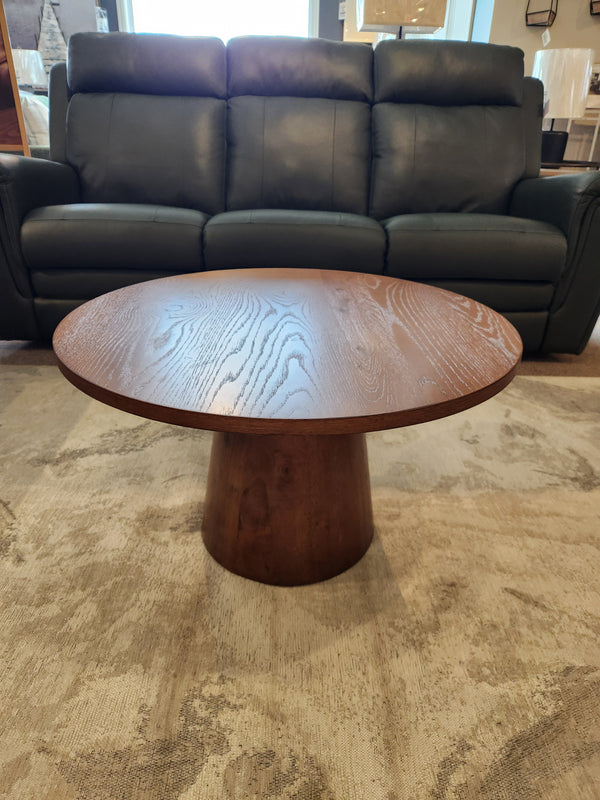 The Donald Choi Rory 29" Coffee Table in black oak veneer sits on a light rug before a dark green sofa.