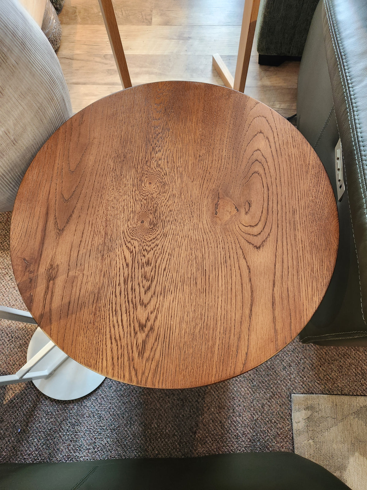 The Rory 20" Chair Side Table by Donald Choi is perfect for small spaces, shown beside a green sofa on carpet.