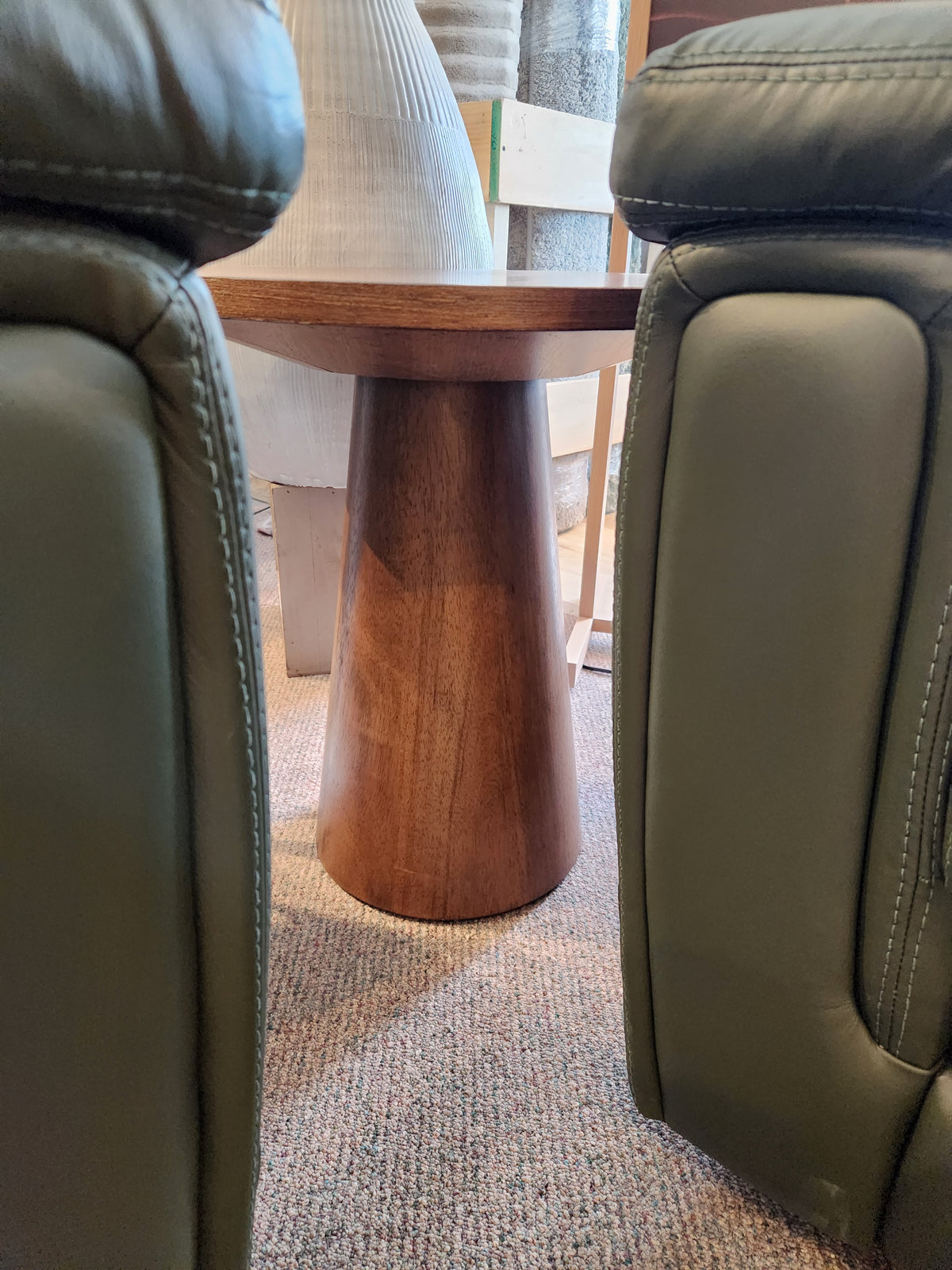 The Donald Choi Rory 20" Chair Side Table sits on carpet between two green upholstered chairs.
