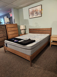 The Palliser EQ3 Monarch Queen Bedframe stands in a bedroom with dressers, lamps, and a winter-themed painting.