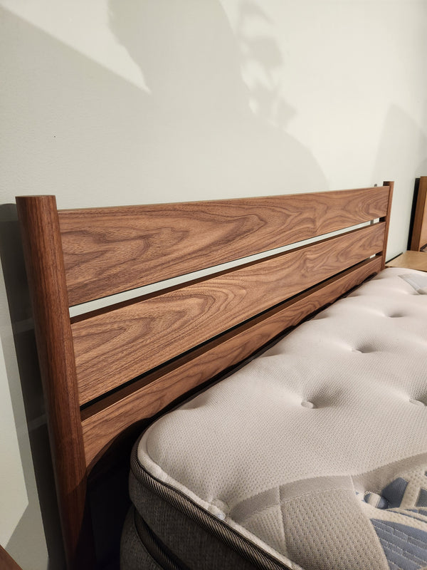 The Palliser EQ3 Monarch Queen Bedframe features a walnut veneer slat headboard and a tufted white mattress.
