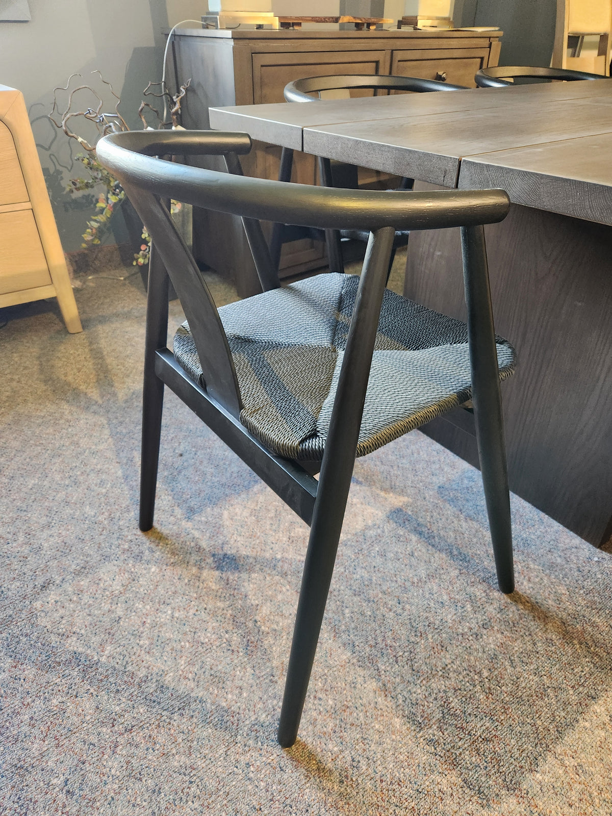 A black wooden chair with a gray woven seat sits by a Palliser EQ3 Homework 5 Piece Dining Table Set on carpet.