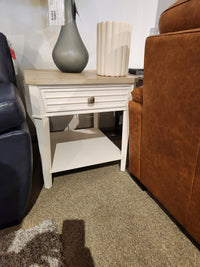 The Magnussen B6310-Echo Isles End Table with drawer and shelf sits between a blue sofa and a brown armchair.
