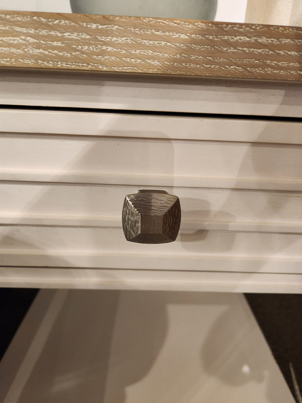 Close-up of a metallic knob on the white grooved front of the Magnussen B6310-Echo Isles End Table.