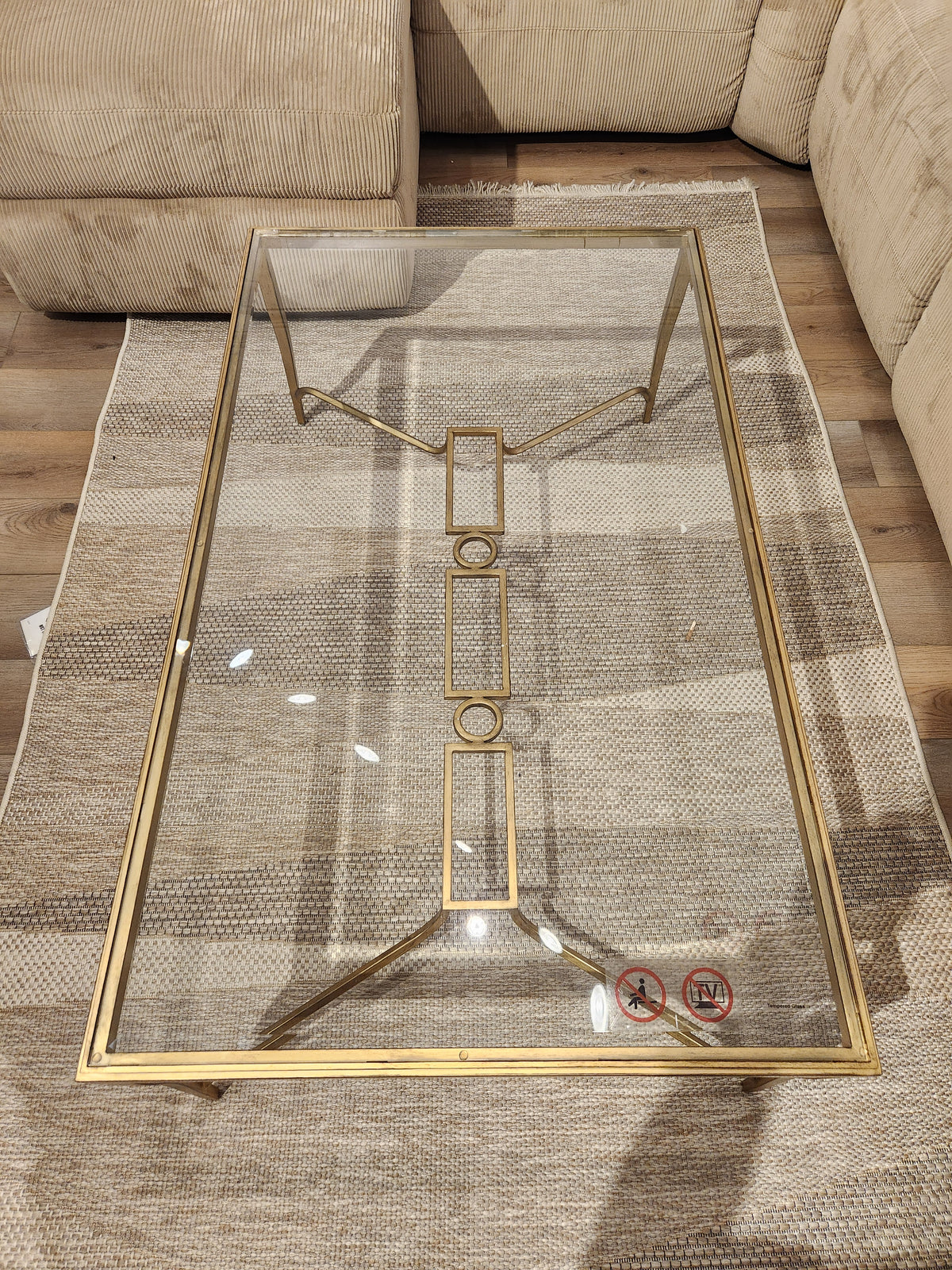 Magnussen T6300 Lorena Cocktail Table with burnished brass finish sits on a beige rug between tan sofas.