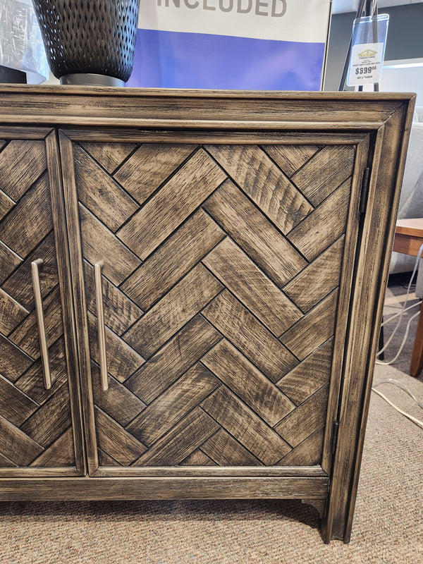 The Jofran Gramercy 2 Door Accent Cabinet features chevron-inlay doors and metal handles.