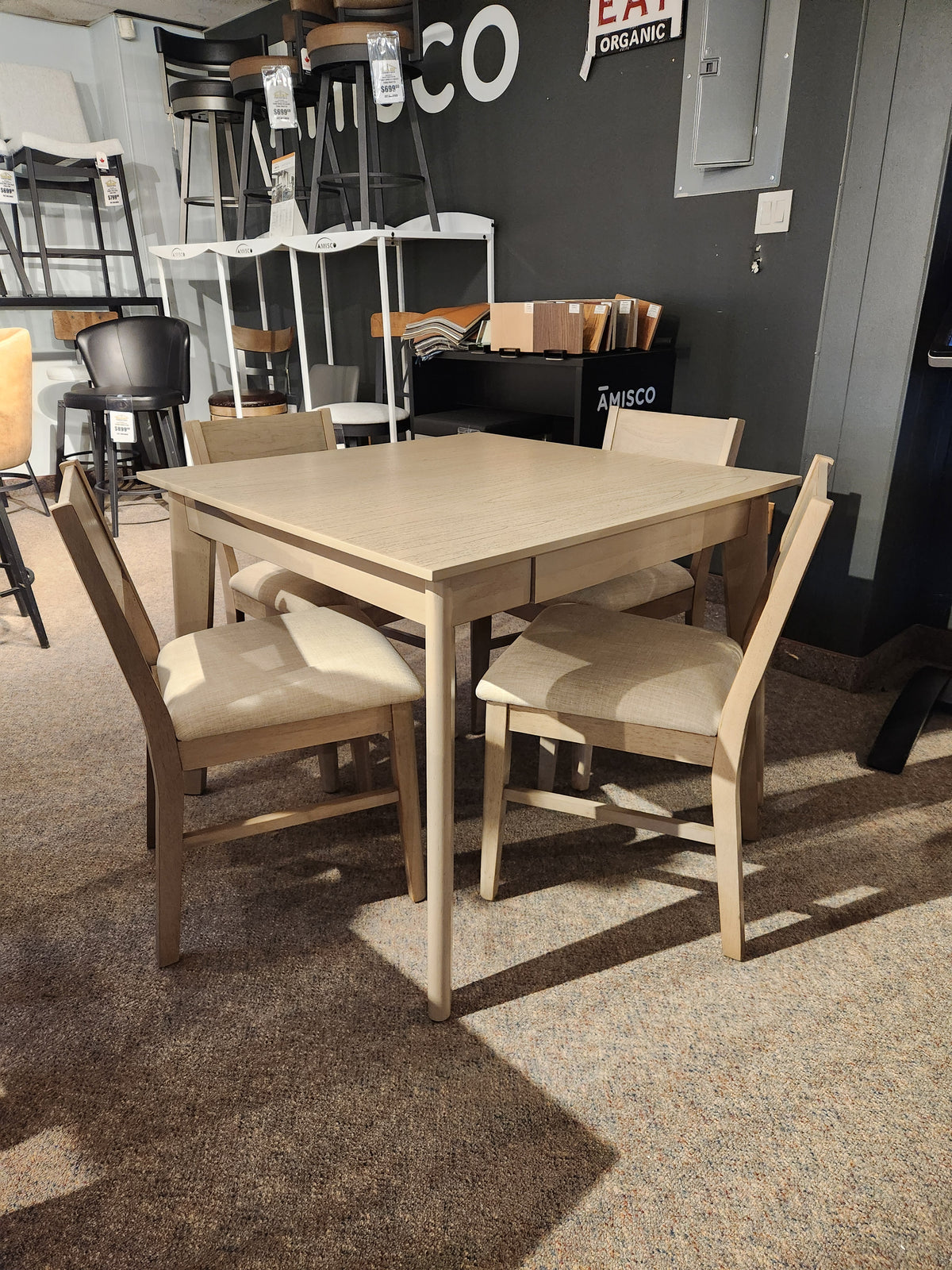 The Donald Choi York Dining Set features a light square table and four matching chairs in a showroom setting.