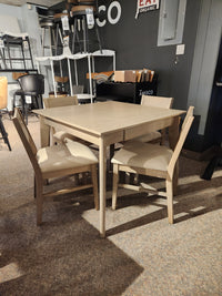 The Donald Choi York Dining Set features a light square table and four matching chairs in a showroom setting.