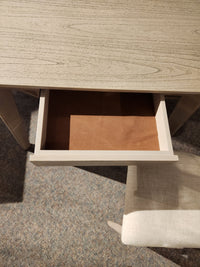 The York Dining Set by Donald Choi includes a desk with an open drawer above a cushioned chair on carpet.