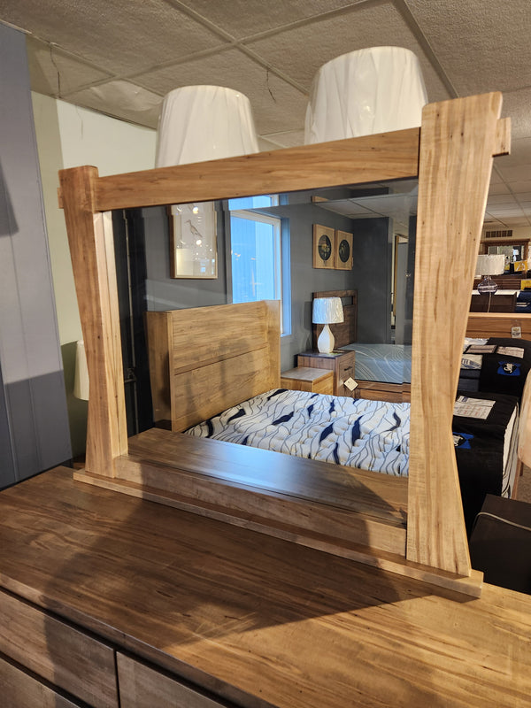 The Handstone JA9 Dresser Mirror reflects a bed and lamps in a showroom, displayed atop a dresser.