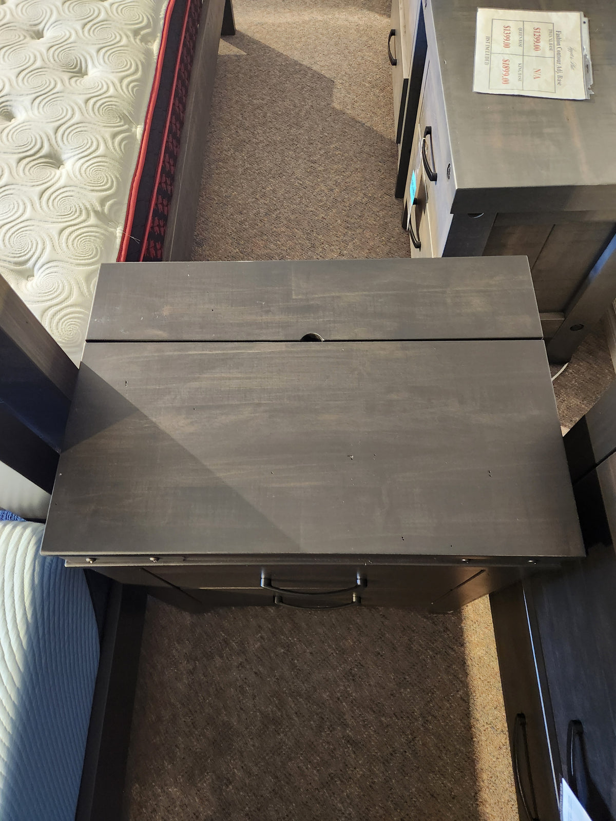 A Handstone Chattanooga Power Nightstand with custom metal hardware sits between beds on a carpeted floor.