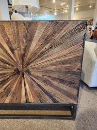 The Jofran 1928 Astral Plains 2 Door Cabinet features a starburst pattern and textured doors, displayed with other decor.