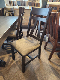 A Handstone RA4284 Rafters Dining chair is placed by a table on a carpeted showroom floor.