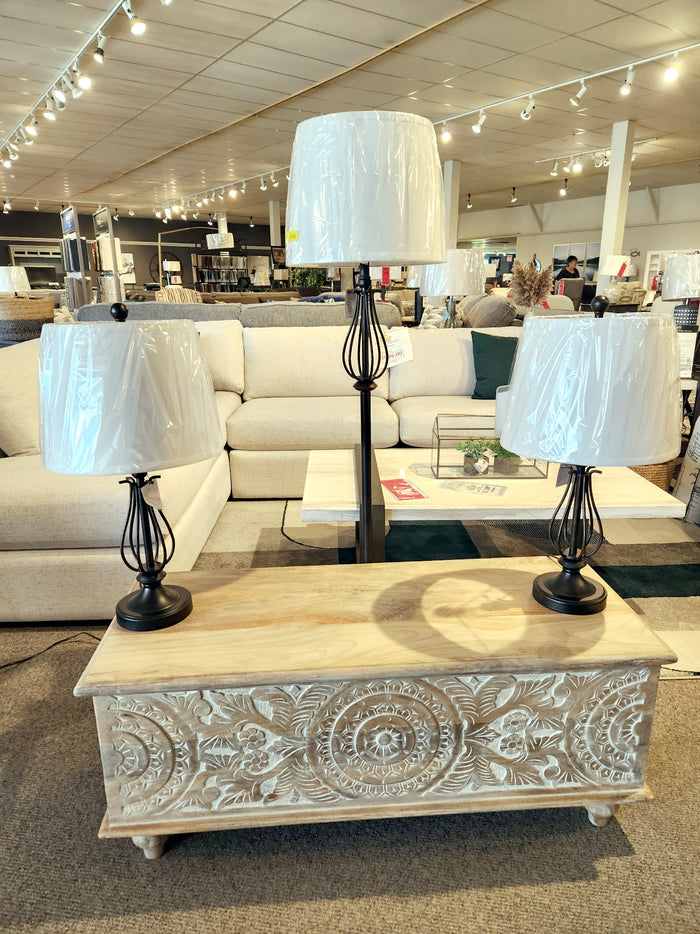 The Ashley L204526 Brycestone Lamp Set with white shades and bronze-tone finish is displayed on a carved wooden chest.