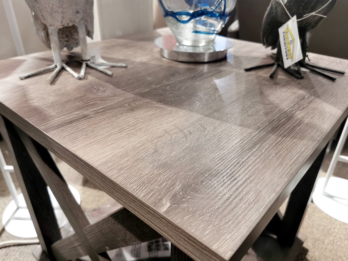 The Ashley Arlenbry End Table features a weathered oak look, bird accents, and glass vase—ideal for modern farmhouse style.