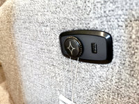 Close-up of a gray textured fabric surface on the comfortable 6NZ57 Derek Power Chair by Best, featuring a black circular button and a USB port, adorned with a star-like logo.